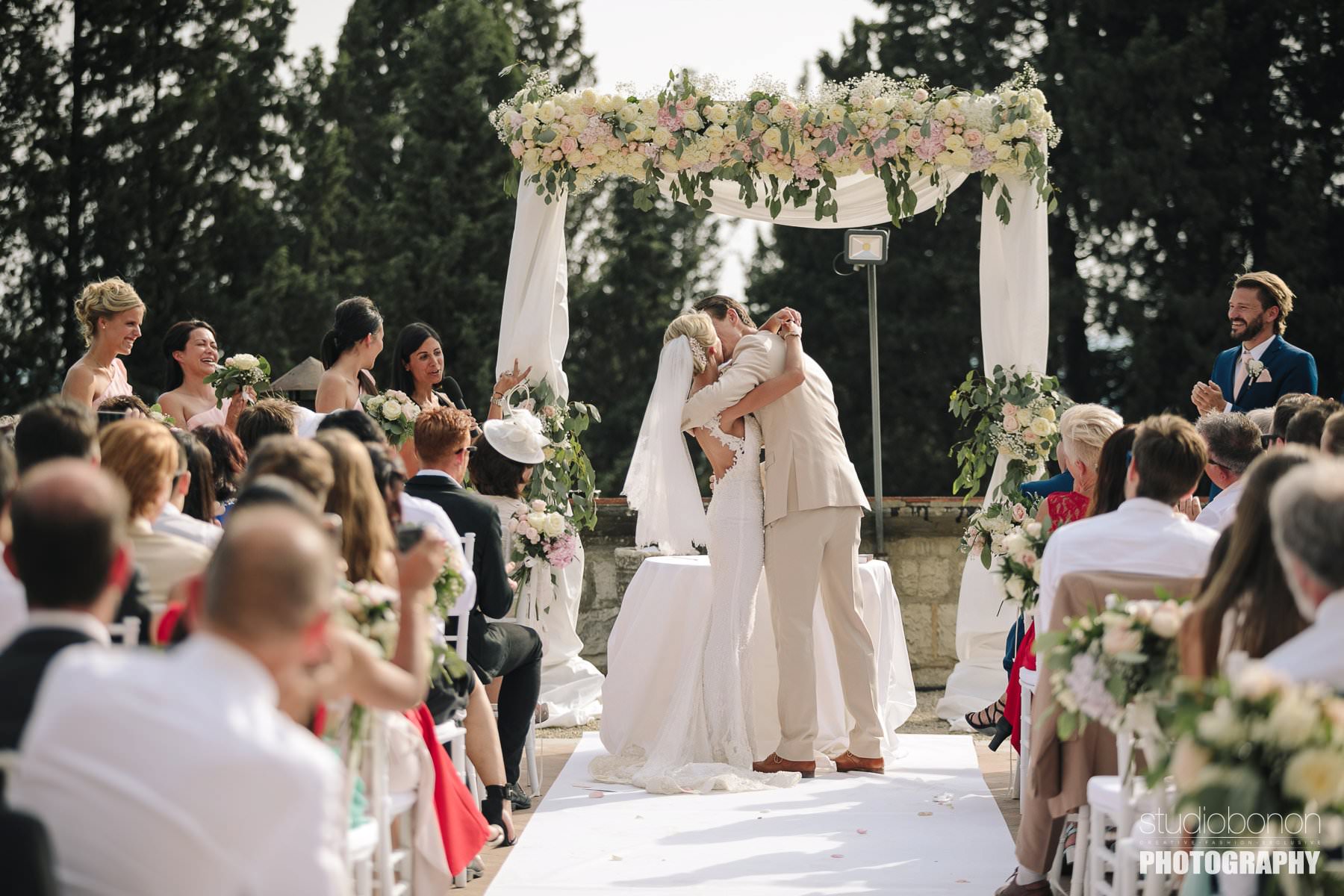 Bride and groom first kiss during outdoor ceremony at Vincigliata Castle into the Florence countryside